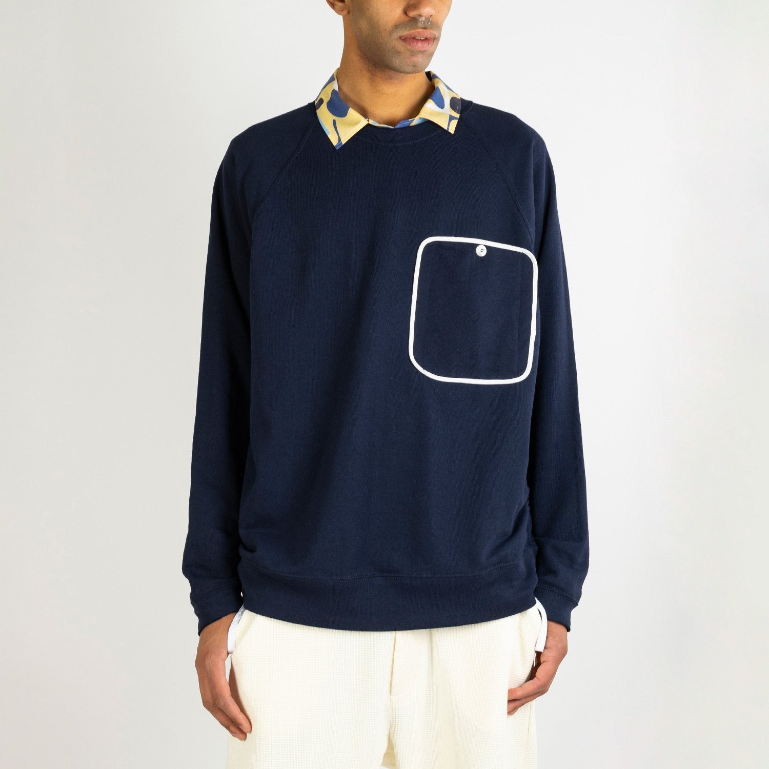 Navy blue sweater with a big white outlined front pocket.