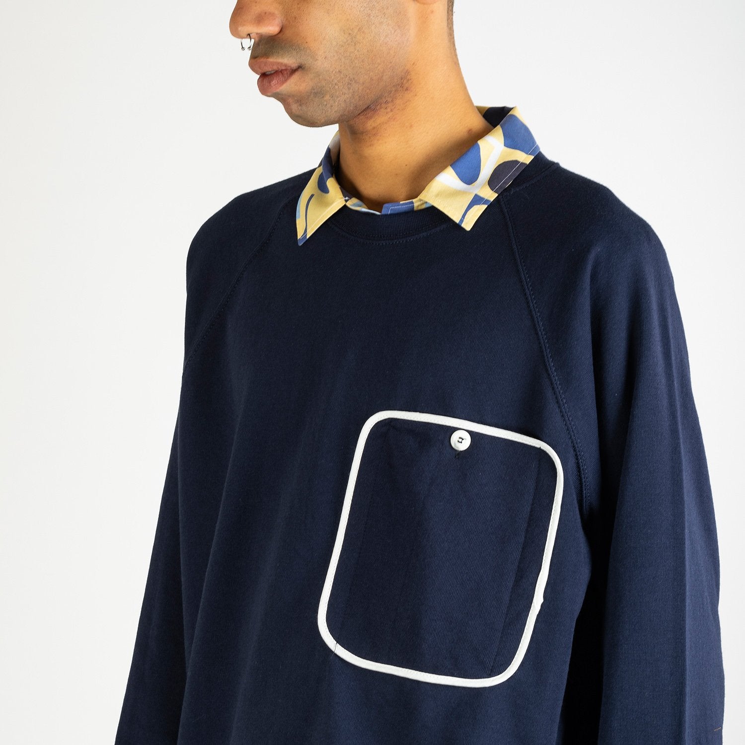 Navy blue sweater with a big white outlined front pocket.